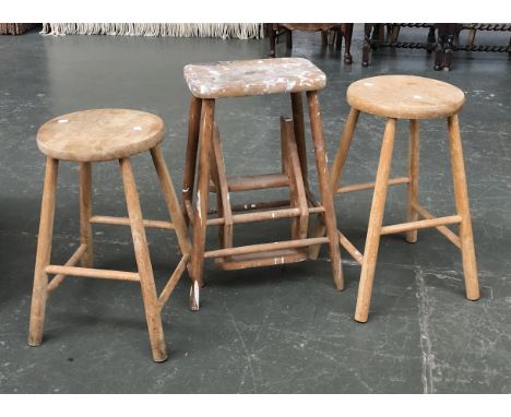 A pair of beech and elm kitchen stools with circular seats, each 56cmH; together with a further stool with fold out steps, 64