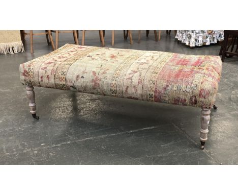 A large OKA upholstered centre stool, on limed effect turned legs and casters, 153cm wide, 87cm deep, 55cm high 