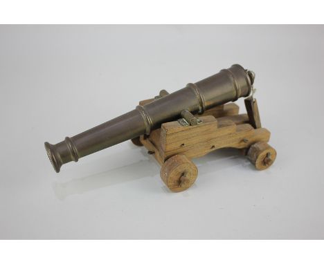 A model of a cannon with brass barrel on wooden support and wheels, 22cm