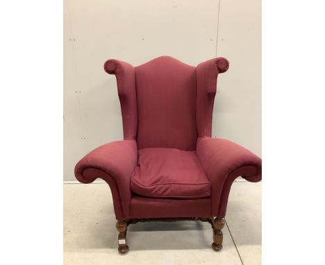 A Queen Anne revival wing armchair with wide scroll arms on turned walnut underframe, width 106cm, depth 70cm, height 120cm. 