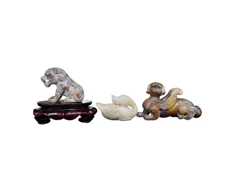 Three Chinese archaistic jade carvings of a winged mythical beast, a duck and a horned seated beast, one stand, largest 13cm 