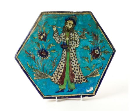 A PERSIAN HEXAGONAL POTTERY TILE20th century
Painted with a bearded figure carrying an axe over his shoulder between flowerin