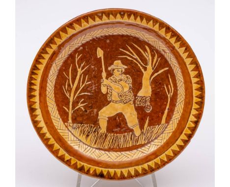 A Welsh [Claypits Pottery] dated slipware dish: decorated in white and brown slips under a lead glaze with a woodsman wieldin