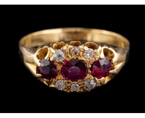 An 18 carat gold ruby and diamond ring,: the three oval cut rubies with old diamonds to the side, stamped 18ct, ring size N.