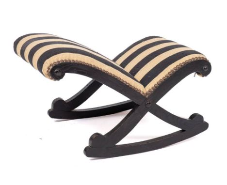 A Regency or George IV ebonised oak rocking gout stool, circa 1820,: with later striped upholstery, brass studded to 'X' form
