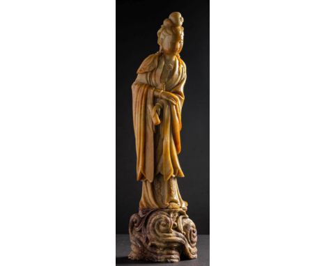 A large Chinese carved soapstone figure of Guanyin: her hair in a high chignon, wearing long flowing robes and holding a scro