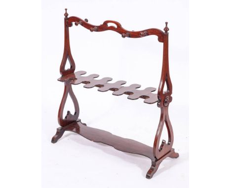 A Victorian mahogany boot stand, mid 19th century,: the serpentine toprail with pierced central handle and eight turned pegs,