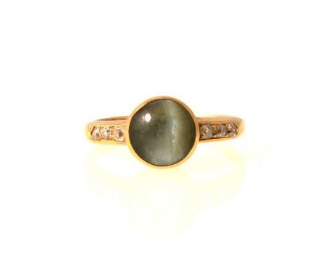 A Chrysoberyl cats eye ring, the 7.4mm round cabochon cut stone collet set in an all yellow gold mount with three old cut dia