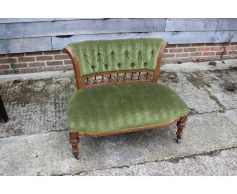 A late 19th century carved walnut showframe two-seat settee, button upholstered in a green velour, on turned supports, 36" wi