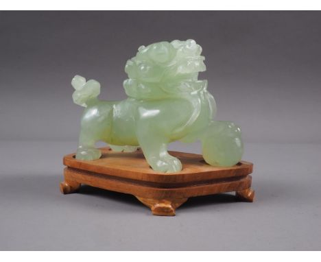A Chinese carved green jade model of a Dog of Fo, on hardwood stand, 3 1/2" high overall 
