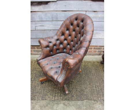An executive's armchair, button upholstered in a brown leather, on quadruple splay supports 