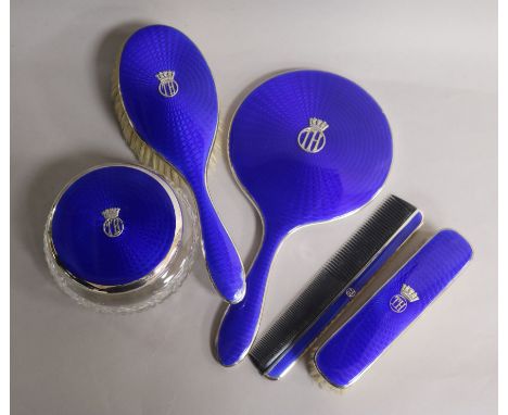 A matched five-piece blue guilloche enamel and silver dressing table set, comprising a hand mirror, hair brush, clothes brush