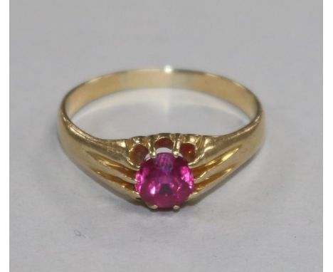 An 18ct gold and synthetic ruby ring, the circular cut stone set between channel-set shoulders, size V.