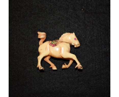 A 19th century Indian carved bone and gem set pendant, as a cantering horse, ruby eyes, ruby, emerald and sapphire set yellow