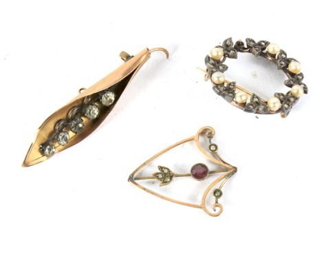 Three antique brooches. Comprising an Art Noveau pendant set with seed pearls and a pink stone, stamped '9ct' (AF), a lily of