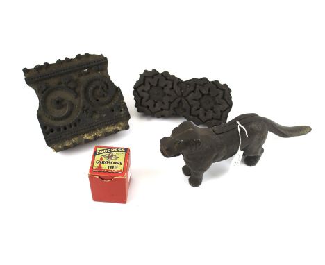 A cast iron nut cracker in the shape of a dog, two printing blocks and a boxed gyroscope. The wooden printing blocks featurin