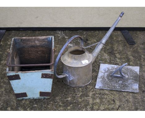 A vintage metal watering can, a sundial and a wooden basket with a single handle. The basket painted green with swing handle,