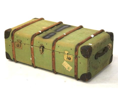 A large mid-century canvas and wooden bound travelling trunk. With green canvas covering and leather carry handles, the brass