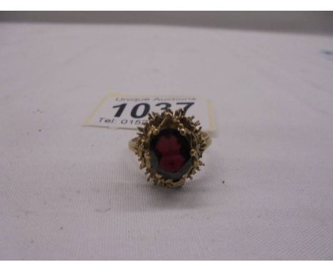 A large oval ruby/garnet? yellow gold ring, size Q half, 5 grams.