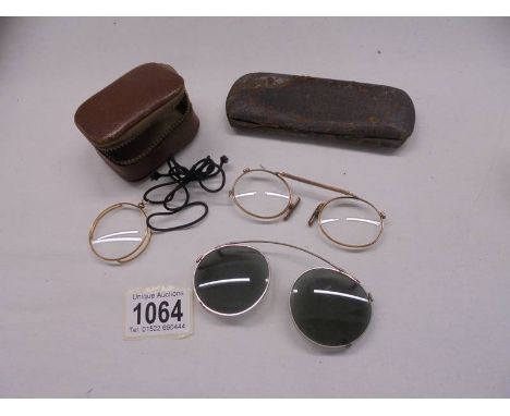 A vintage gilded monacle eye piece, clip on sunglasses and one other.
