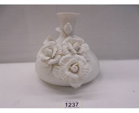 A white ceramic vase with applied roses.