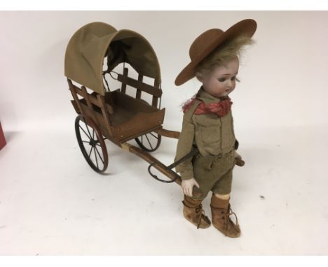 A late 19th early 20th century Automaton in the form of a small boy, possibly a boy scout, pulling a small covered wagon. The