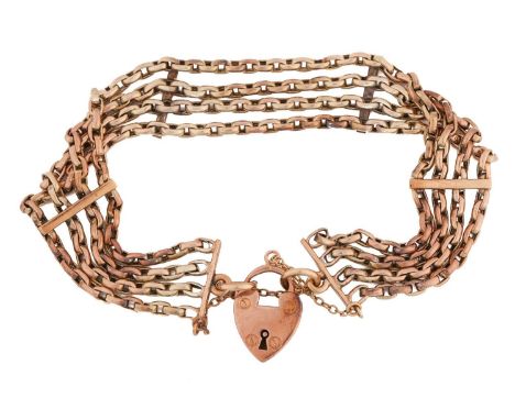 A four-row bracelet with heart padlock, comprising four strands of yellow metal cable links with bar spacers, fastened with a