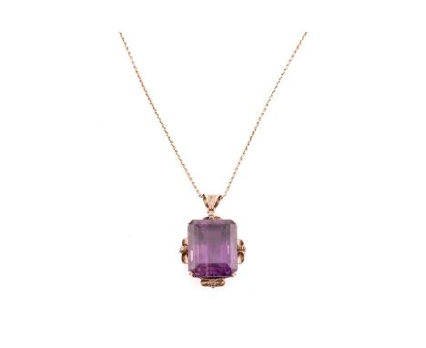 A large amethyst pendant on chain, contains an octagonal step-cut amethyst of 19.6 x 15.9 x 14.2 mm, claw-set in a volute mou