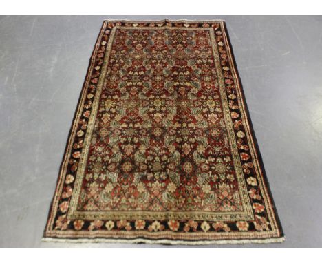 A Mahal rug, North-west Persia, mid-20th century, the red field with overall herati, within a charcoal flowering vine border,