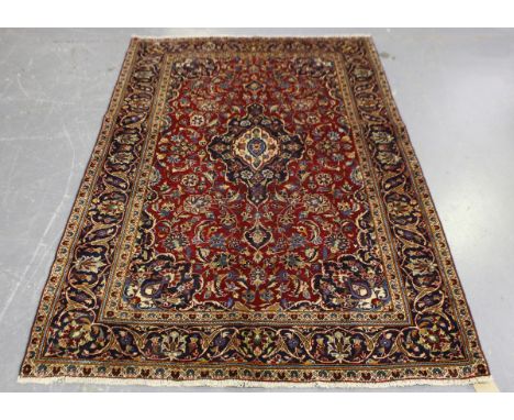 A Kashan rug, Central Persia, mid-20th century, the claret field with a shaped medallion, within a midnight blue palmette bor