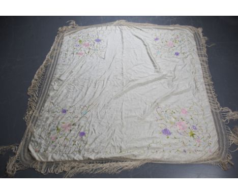 An early 20th century cream silk shawl, embroidered with polychrome flowers, 158cm x 158cm, within a long fringed border.Buye