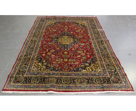 A Mashad carpet, Central Persia, mid-20th century, the claret field with a shaped medallion, within a blue palmette border, 2