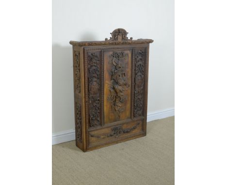 An antique carved Wall Cabinet with coat of arms surmount, the single door carved in relief depicting an artist’s easel and a