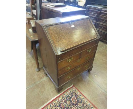 An 18th Century oak Bureau, the moulded fall revealing a stepped and welled interior with pigeon holes and drawers, over two 
