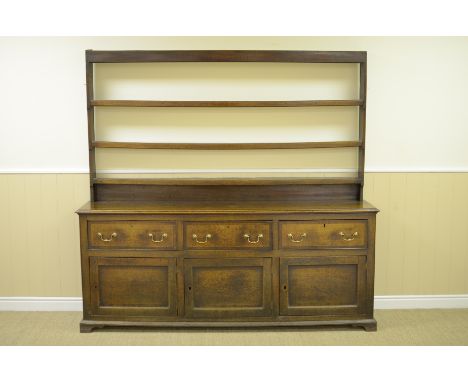 An antique oak Dresser with boarded rack, the enclosed base fitted three drawers above three solid panelled doors all cross-b