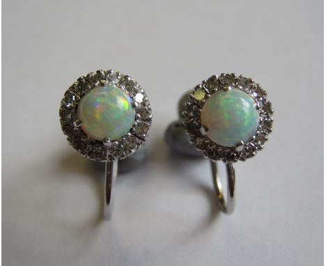 A pair of Opal and Diamond Earrings each claw-set circular cabochon within frame of pavé-set eight-cut diamonds on screw fitt