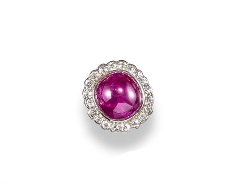 A cabochon ruby and diamond cluster ring, the oval~shaped ruby weighs approximately 16.50cts and is set within a surround of 