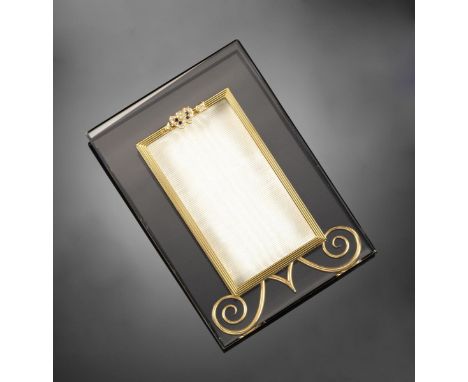 A gold and rock crystal rectangular frame by Asprey, the fluted yellow gold borders surmounted with an entwined heart and arr