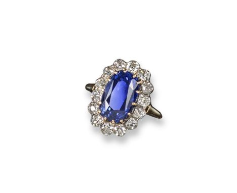 A sapphire and diamond cluster ring, the oval~shaped sapphire weighs approximately 7.90 carats and is set within a surround o