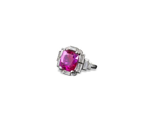 An Art Deco ruby and diamond ring, the cushion~shaped ruby weighs 6.17 carats and is set in platinum and white gold with ten 