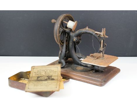 19th Century Victorian Wilcox &amp; Gibbs hand sewing machine of cast iron construction raised on a wooden base, maker plaque