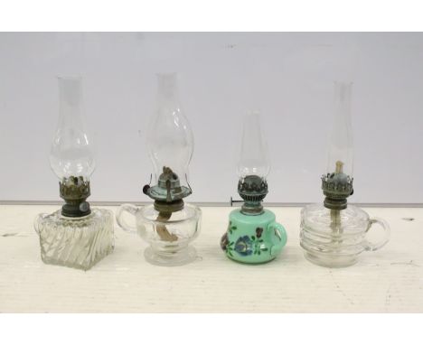 Group of four 19th Century hand held oil lamps to include a green glass lamp with hand painted florals, and three with fluted