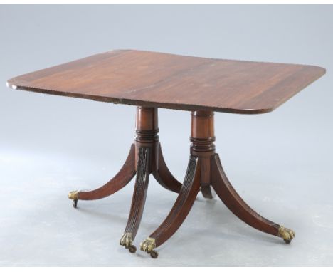 A GEORGE III STYLE MAHOGANY TWIN PEDESTAL DINING TABLE, the rectangular top with rounded corners, raised on a ringed gun barr