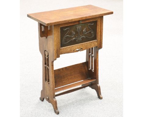 AN ARTS AND CRAFTS OAK DESK, the rectangular top above a hinged fall front with inset stylised foliate repousse panel, openin
