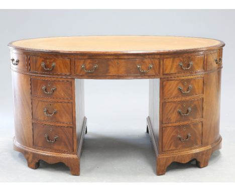 A GEORGE III STYLE LEATHER INSET MAHOGANY OVAL PARTNERS DESK, the moulded rectangular top enclosing a gilt tooled leather ins