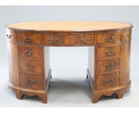 A GEORGE III STYLE LEATHER INSET MAHOGANY OVAL PARTNERS DESK, the moulded rectangular top enclosing a gilt tooled leather ins