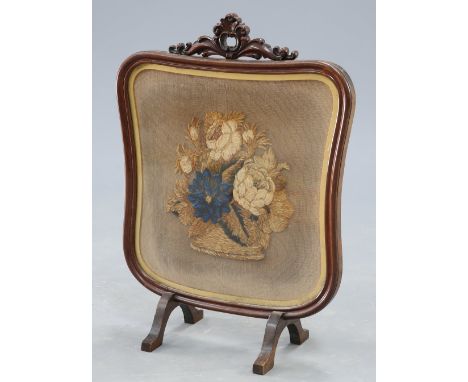 A 19TH MAHOGANY AND NEEDLEWORK FIRESCREEN, the cartouche shaped banner decorated with a basket of flowers. 66cm high by 50cm 