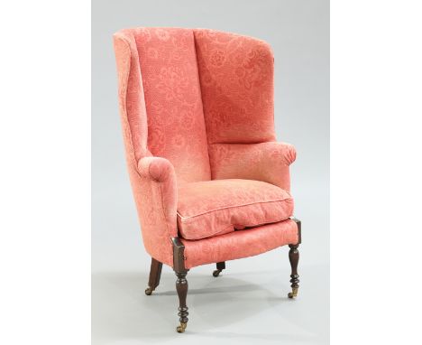 A LATE VICTORIAN MAHOGANY AND UPHOLSTERED WING-BACK ARMCHAIR, raised on baluster and ring turned legs, moving on castors. Hei