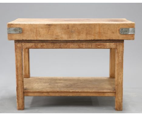 A LARGE BEECH BUTCHERS BLOCK, with metal bound corners, raised on a pine base with chamfered square section legs and shelf st