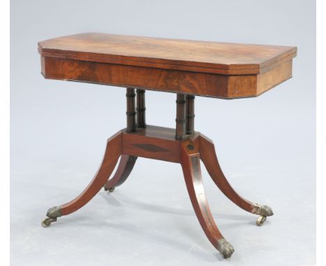 A REGENCY MAHOGANY FOLDOVER CARD TABLE, the flame mahogany top with canted corners, raised on two pairs of ringed columns iss